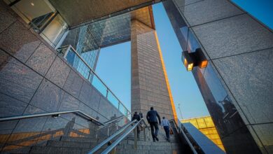 Two businessmen climb a sleek, modern high-rise staircase, symbolizing professional growth.