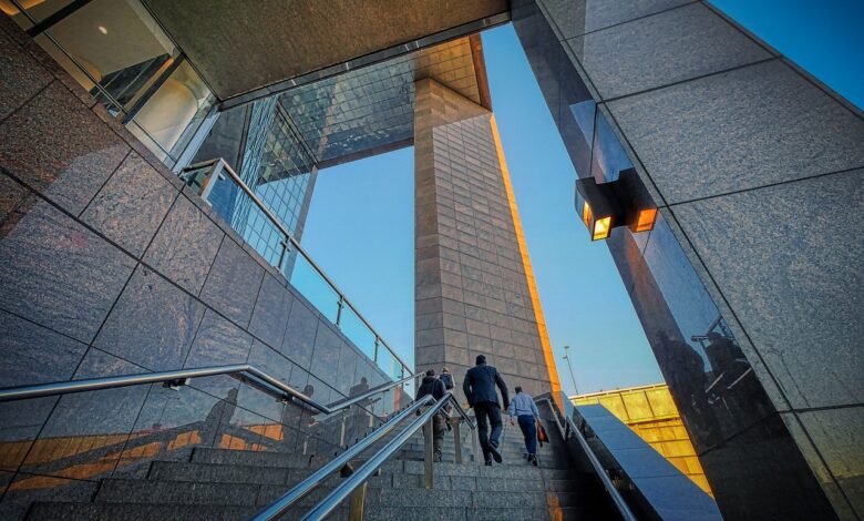 Two businessmen climb a sleek, modern high-rise staircase, symbolizing professional growth.