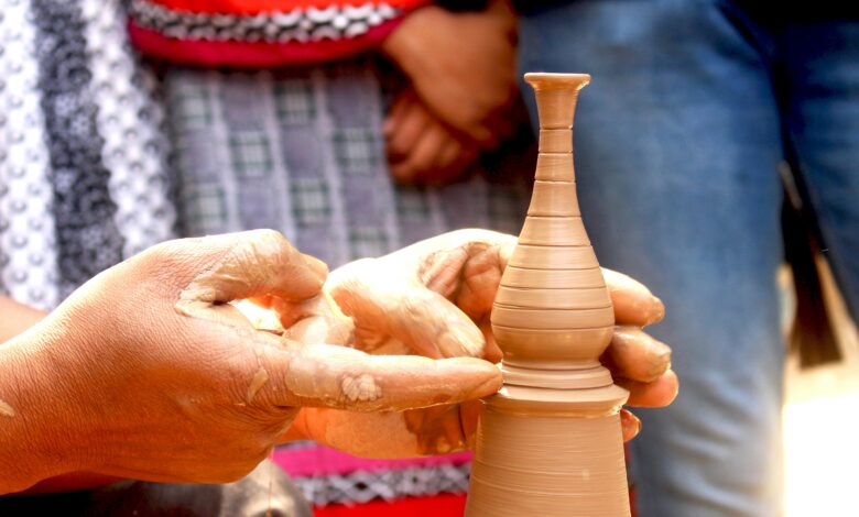 Hands meticulously shaping a delicate clay vase on a pottery wheel
