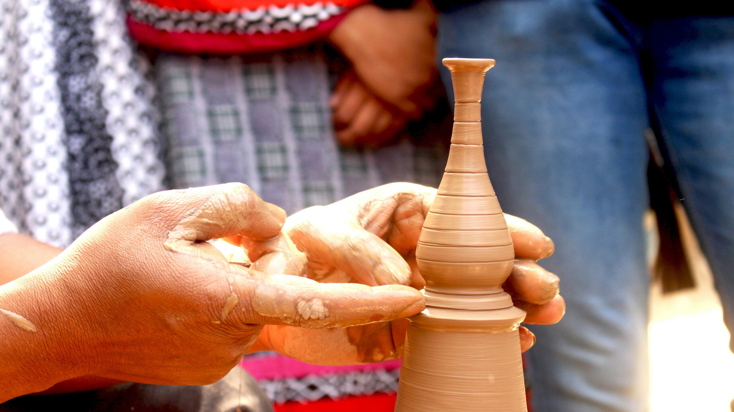 Hands meticulously shaping a delicate clay vase on a pottery wheel