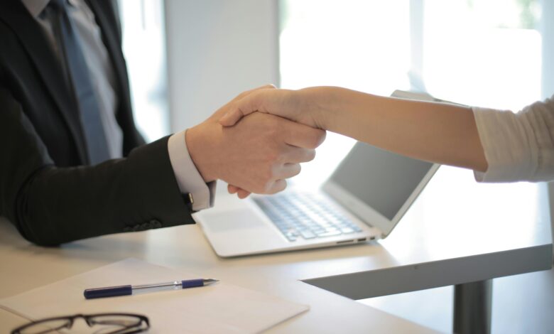 Close-up of a professional handshake over a laptop during a business meeting in an office.
