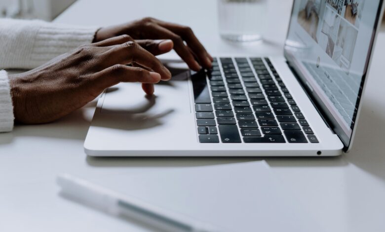 Hands typing on a sleek laptop keyboard; modern technology in use.