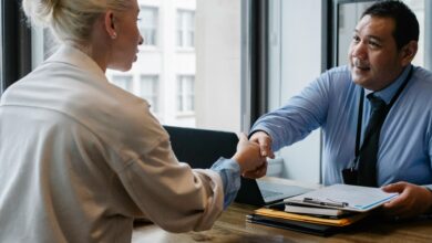 Two professionals in an office setting shaking hands after a business agreement.