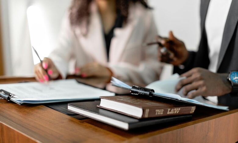 Two lawyers reviewing documents with law books on a desk. Professional legal environment.